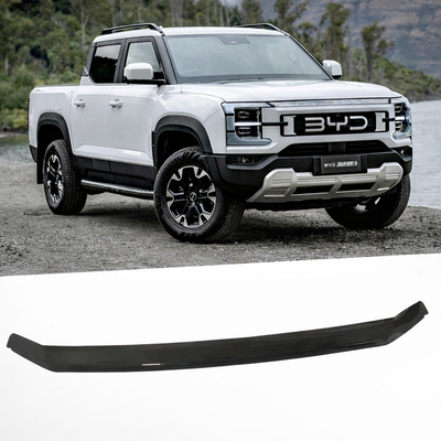 White BYD truck on a road with a black car bumper lip in the foreground.